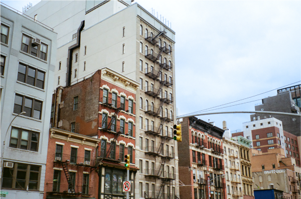 Large red-brick buildings side-by-side, against an overcast grey sky.