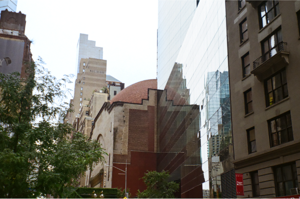 Shot of domed building reflected on side of mirror-like skyscraper.