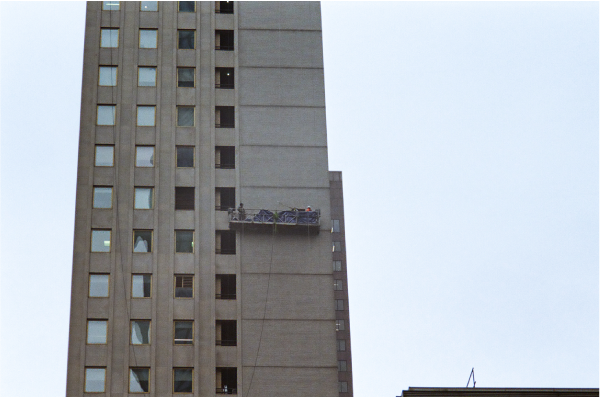 Vertical shot of window cleaners on side of skyscraper.