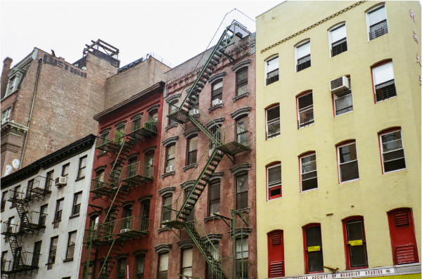 Colorful tenement buildings side-by-side, against an overcast grey sky.